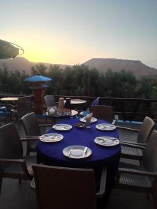 een blauwe tafel met borden en servetten op een patio bij Hotel restaurant ait saderat in Boumalne
