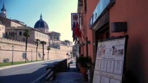 uma placa na lateral de um edifício ao lado de uma rua em San Gabriele em Loreto
