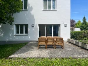 dos bancos de madera sentados fuera de una casa blanca en Traumgarten in Traumlage - 25 Minuten ins Zentrum, en Viena