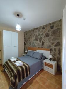 a bedroom with a bed and a stone wall at Casa del Caño 