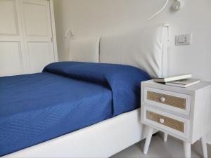 a bed with a blue blanket and a night stand at La casa di Ge e Fra in Galatone