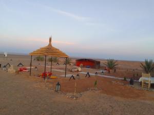 a tent and an umbrella in the desert at Camp Familia Erg Chebbi in Merzouga