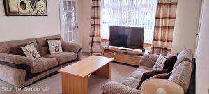 a living room with couches and a flat screen tv at Curlew - Port Seton in Port Seton