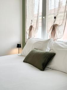 a bed with white sheets and a green pillow on it at Casa Febo, in centro con parcheggio privato a 200 mt dal mare in Bordighera