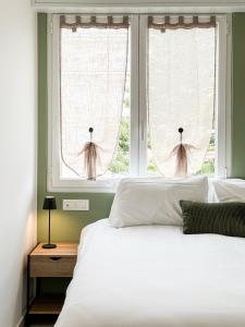 a bedroom with a white bed and two windows at Casa Febo, in centro con parcheggio privato a 200 mt dal mare in Bordighera