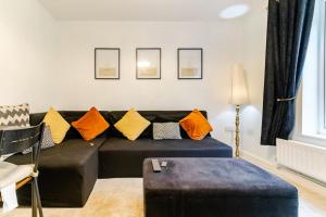 a living room with a black couch with orange pillows at A&S Properties, No guest fees, Bank transfe deposit available in Fallings Park