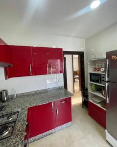 Il comprend une cuisine équipée de placards rouges et d'un réfrigérateur rouge. dans l'établissement Appartement Kariat Cabo, à Neerpelt