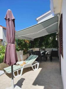 een patio met een parasol en een tafel en stoelen bij Apartman Zvonimir with a beautiful sunset in Silba