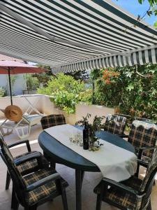 een tafel en stoelen op een patio met een parasol bij Apartman Zvonimir with a beautiful sunset in Silba