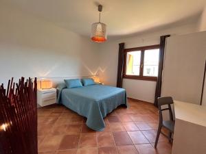 een slaapkamer met een blauw bed en een raam bij Casa vacanze - Le Bacche di Maiorca in Budoni