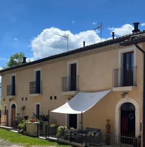 a building with a white umbrella in front of it at La Dimora dei Baldi - Rooms & Relax in Fagnano Alto