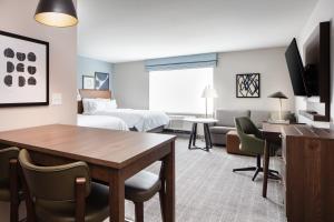 a hotel room with a table and a bedroom at Staybridge Suites - Iowa City - Coralville, an IHG Hotel in Coralville