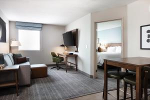 コーラルビルにあるStaybridge Suites - Iowa City - Coralville, an IHG Hotelのベッドとリビングルームが備わるホテルルームです。