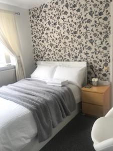 um quarto com uma cama com papel de parede floral em fAiRy Dell Guesthouse with cozy lockable rooms, tv, free tea tray, free wifi, free parking em Oakenshaw