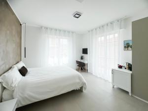 a white bedroom with a bed and a desk at Casa Febo, in centro con parcheggio privato a 200 mt dal mare in Bordighera