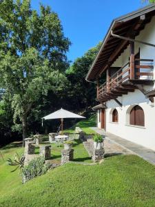 ein Haus mit einem Tisch und einem Sonnenschirm im Hof in der Unterkunft Casa Birtukan in Massino Visconti