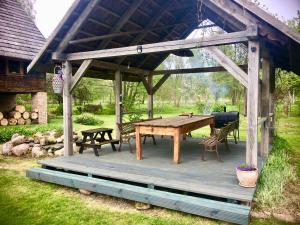a wooden pavilion with a wooden table and chairs at Griķi in Kalnišķi