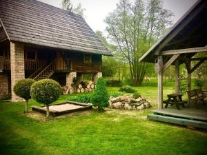 a yard with a house with a picnic table and trees at Griķi in Kalnišķi