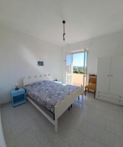 une chambre blanche avec un lit et une fenêtre dans l'établissement Casa torelli azzurro, à Sellia Marina