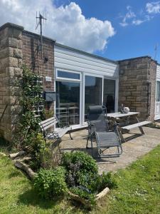 a patio with a table and a chair next to a building at 107 Brambles Chine, Holiday Coastal Chalet in Freshwater