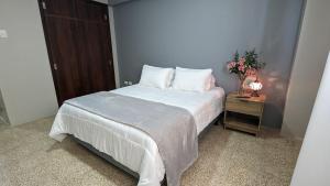 a bedroom with a bed and a night stand with a vase of flowers at Suite 618 Downtown Guayaquil- Centro de la Ciudad in Guayaquil +19 photos