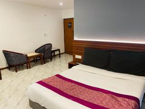 Royal Presidency Inn في لاكناو: غرفة فندقية بسرير وطاولة وكراسي