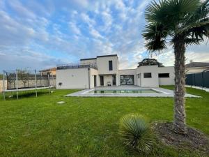 マコンにあるlocation villa moderne piscineの庭のヤシの木がある大きな白い家