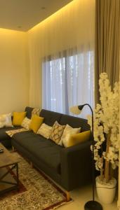 uma sala de estar com um sofá azul com almofadas amarelas em فيلا رسن em Al Hada