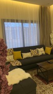 uma sala de estar com um sofá preto em frente a uma janela em فيلا رسن em Al Hada
