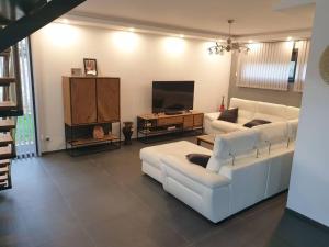 ein Wohnzimmer mit weißen Sofas und einem TV in der Unterkunft location villa moderne piscine in Mâcon