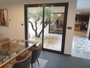 マコンにあるlocation villa moderne piscineのガラスのテーブルと壁に木が飾られたダイニングルーム