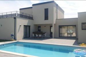 ein Haus mit einem Pool vor einem Haus in der Unterkunft location villa moderne piscine in Mâcon