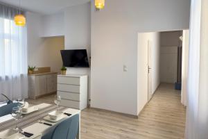 a white living room with a table and a television at Apartamenty Emilia 2 in Gniezno