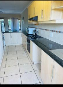 a kitchen with white cabinets and black counter tops at Franjipani in Margate