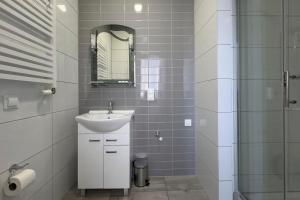 a white bathroom with a sink and a shower at Apartamenty Emilia 2 in Gniezno +18 photos