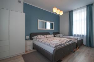 a bedroom with two beds and a blue wall at Apartamenty Emilia 2 in Gniezno