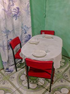 a table with two red chairs and a white table with plates on it at SMITH'S BNB ROOMS in Georgetown
