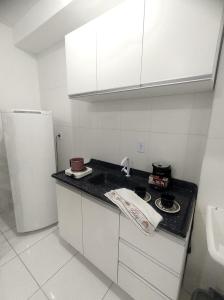 eine Küche mit einer schwarzen Arbeitsplatte und einem Kühlschrank in der Unterkunft AP Studio novo. Prático para até 4 pessoas, Térreo in Paranaguá