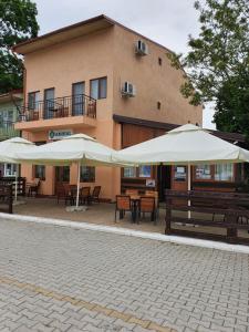 two tables and umbrellas in front of a building at Casa Amiral in Sulina