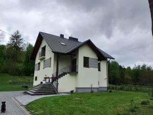a white house with a black roof at Apartament z ogrodem in Przemyśl