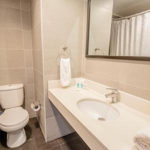 bagno con lavandino, servizi igienici e specchio di HOTEL GAVINA EXPRESS IQUIQUE a Iquique
