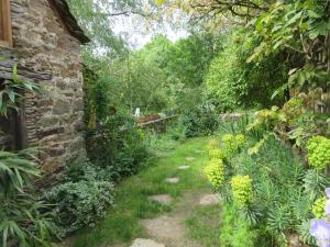 a garden with a brick wall and a yard with plants at Maison de la Carrérie, gîte de charme à Calmont 12450 in Calmont