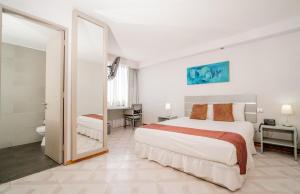 una camera bianca con un grande letto e uno specchio di HOTEL GAVINA EXPRESS IQUIQUE a Iquique