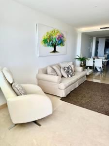 ein Wohnzimmer mit einem weißen Sofa und einem Baum in der Unterkunft La Floresta Sur Apartment Sunshine1 in La Mairena