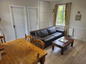 un salon avec un canapé en cuir et une table dans l'établissement Peaceful Farm Cottage in Menlough near Mountbellew, Ballinasloe, Athlone & Galway, à Galway