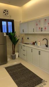a kitchen with white cabinets and a potted plant at فيلا رسن in Al Hada