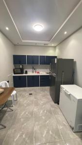 a large kitchen with blue cabinets and a refrigerator at درة العروس فيلا بشاطئ رملي خاص in Durat  Alarous