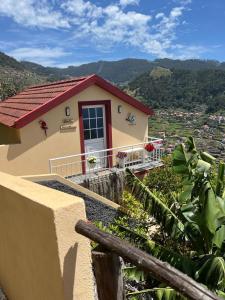 una pequeña casa con una puerta roja en una colina en Tropical House, en Ribeira Brava