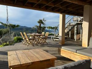 eine Terrasse mit einem Holztisch, Stühlen und einer Schaukel in der Unterkunft Villa Pura Corsica with sea view and private pool in Conca