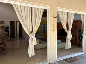 a sliding glass door with curtains in a living room at Praia de Itamambuca- Casa charmosa e iluminada in Ubatuba